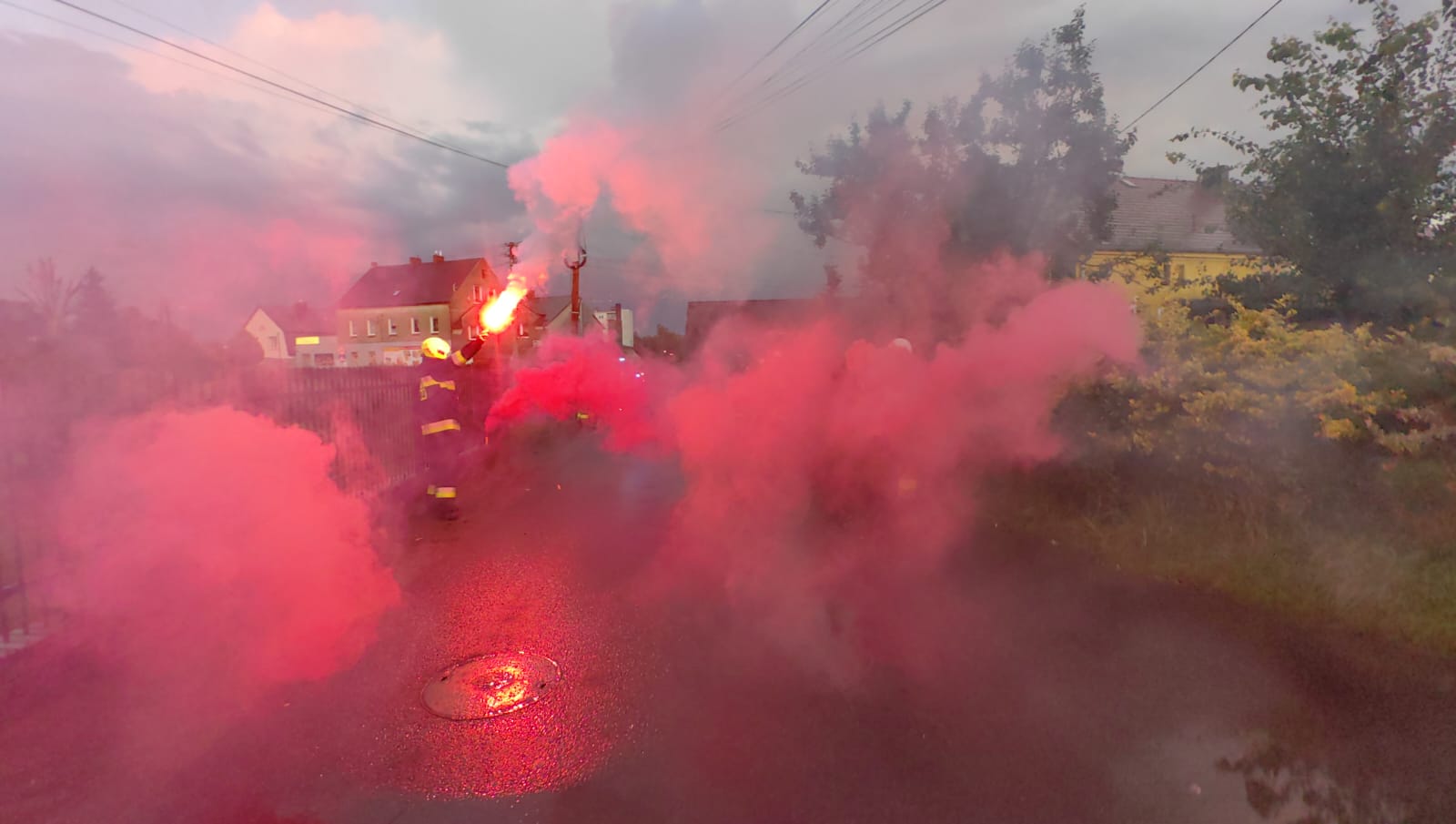 Zdjęcie Strażaków z odpalonymi czerwonymi racami